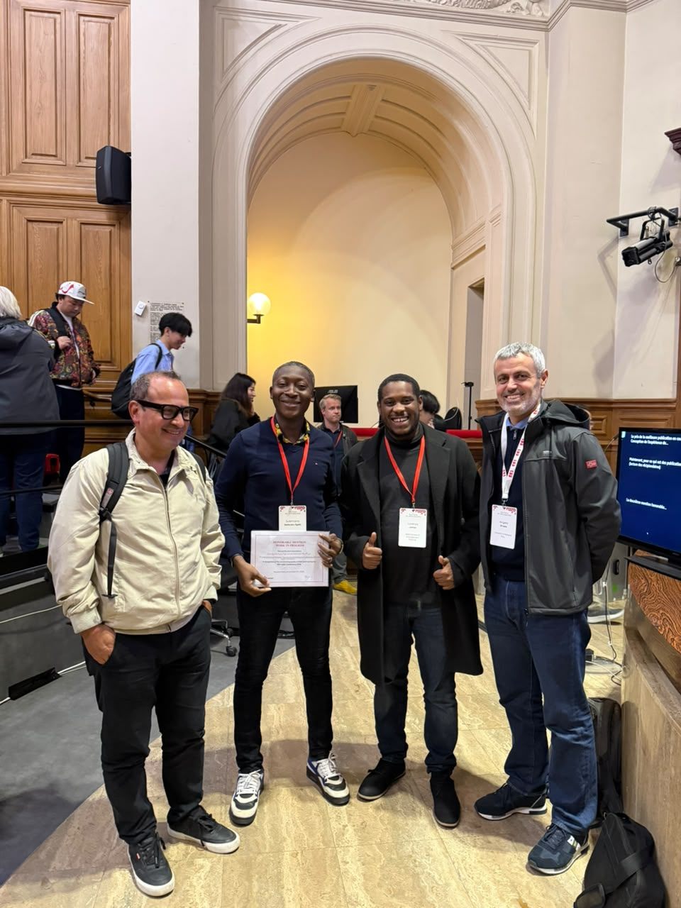Esteban Clua, Sulemana Bankuoru Egala holding the Honourable Mention certificate, Lorenzo James and Angelo Di Iorio in the conference hall